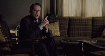 Movie still from “The Sixth Sense” (1999), directed by M. Night Shyamalan – A man sitting on a chair in a living room; Medium shot, High angle