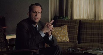 Movie still from “The Sixth Sense” (1999), directed by M. Night Shyamalan – A man sitting on a couch in a room; Medium shot, Low angle