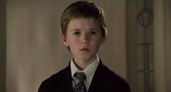 Movie still from “The Sixth Sense” (1999), directed by M. Night Shyamalan – A young boy wearing a suit and a tie; Close Up shot, High angle