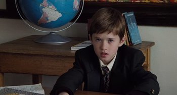 Movie still from “The Sixth Sense” (1999), directed by M. Night Shyamalan – A boy in a suit and tie sitting at a desk; Close Up shot, High angle