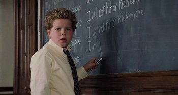 Movie still from “The Sixth Sense” (1999), directed by M. Night Shyamalan – A boy in a dress shirt and tie is writing on a chalkboard; Medium shot, High angle