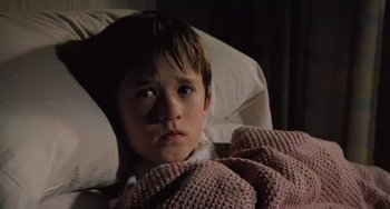 Movie still from “The Sixth Sense” (1999), directed by M. Night Shyamalan – A young boy laying in a bed with a blanket; Close Up shot, High angle