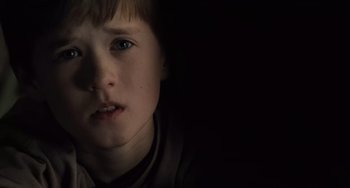 Movie still from “The Sixth Sense” (1999), directed by M. Night Shyamalan – A young boy with blue eyes stares into the camera; Close Up shot, Low angle