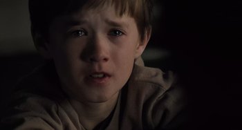 Movie still from “The Sixth Sense” (1999), directed by M. Night Shyamalan – A child with a sad look on his face; Close Up shot, High angle