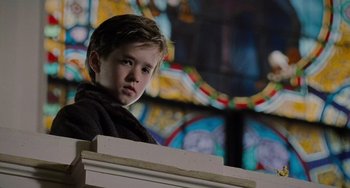Movie still from “The Sixth Sense” (1999), directed by M. Night Shyamalan – A young boy standing in front of a stained glass window; Close Up shot, Low angle