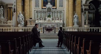 Movie still from “The Sixth Sense” (1999), directed by M. Night Shyamalan – Two people sitting in a large church with pews; Extreme Wide shot, High angle