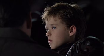Movie still from “The Sixth Sense” (1999), directed by M. Night Shyamalan – A young boy with blue eyes stares into the distance; Close Up shot, Over the shoulder angle