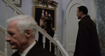 Two men and a woman standing at the bottom of a staircase