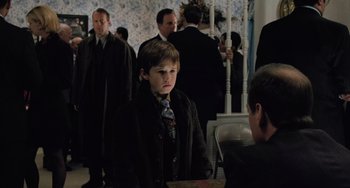 Movie still from “The Sixth Sense” (1999), directed by M. Night Shyamalan – A young boy in a suit and tie; Medium shot, Over the shoulder angle