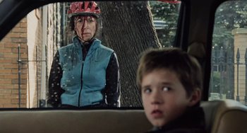 Movie still from “The Sixth Sense” (1999), directed by M. Night Shyamalan – A boy looks in the mirror of a car while an older woman wears a helmet; Close Up shot, Over the shoulder angle