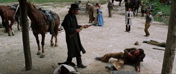 Movie still from “The Specialists” (1969), directed by Sergio Corbucci – A group of people standing on a dirt field; Wide shot, Over the shoulder angle