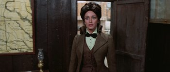 Movie still from “The Specialists” (1969), directed by Sergio Corbucci – A woman wearing a suit and bow tie in front of a door; Medium shot, Over the shoulder angle