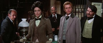 Movie still from “The Specialists” (1969), directed by Sergio Corbucci – A man and a woman standing next to each other in a room; Medium shot, Low angle