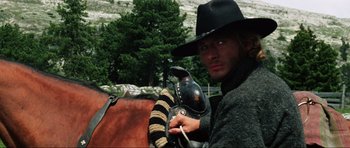 Movie still from “The Specialists” (1969), directed by Sergio Corbucci – A man wearing a black hat is sitting on the back of a horse; Close Up shot, Low angle