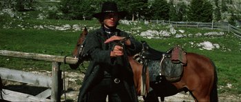 Movie still from “The Specialists” (1969), directed by Sergio Corbucci – A man holding a gun while standing next to two horses; Medium shot, Low angle