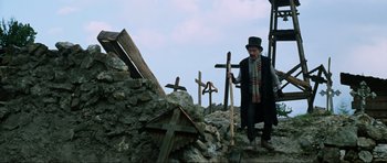 Movie still from “The Specialists” (1969), directed by Sergio Corbucci – A man in a top hat and a scarf standing next to a pile of rocks; Wide shot, Low angle