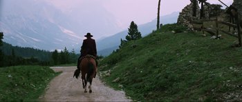 Movie still from “The Specialists” (1969), directed by Sergio Corbucci – A man riding on the back of a horse down a dirt road; Wide shot, Low angle
