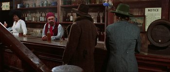 Movie still from “The Specialists” (1969), directed by Sergio Corbucci – A man in a hat is standing at a bar; Medium shot, Over the shoulder angle