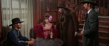 Movie still from “The Specialists” (1969), directed by Sergio Corbucci – A man and a woman are standing at a table with a drink; Medium shot, Over the shoulder angle