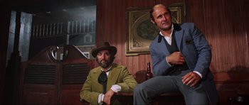 Movie still from “The Specialists” (1969), directed by Sergio Corbucci – Two men in suits and hats sitting next to each other in a room; Medium shot, Low angle