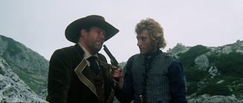 Movie still from “The Specialists” (1969), directed by Sergio Corbucci – Two men dressed in medieval clothing , one holding a gun and the other holding a pistol; Medium shot, Over the shoulder angle