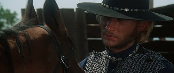 Movie still from “The Specialists” (1969), directed by Sergio Corbucci – A man in a cowboy hat and a chain mail vest; Close Up shot, Over the shoulder angle