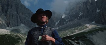 Movie still from “The Specialists” (1969), directed by Sergio Corbucci – A man wearing a hat and a chain mail vest holding a cigarette; Medium shot, Low angle