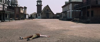 Movie still from “The Specialists” (1969), directed by Sergio Corbucci – A man laying on the ground in a deserted town; Extreme Wide shot, High angle