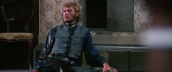 Movie still from “The Specialists” (1969), directed by Sergio Corbucci – A man sitting on the ground wearing a chain mail vest; Medium shot, Low angle
