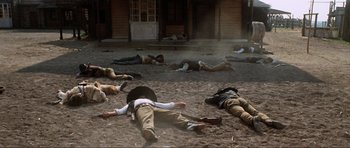 Movie still from “The Specialists” (1969), directed by Sergio Corbucci – A group of people laying on the ground in the dirt; Wide shot, High angle