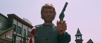 Movie still from “The Specialists” (1969), directed by Sergio Corbucci – A man holding a gun while standing in front of a building; Close Up shot, Low angle