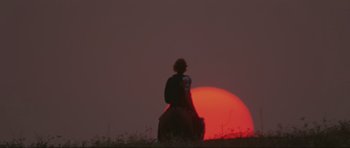 Movie still from “The Specialists” (1969), directed by Sergio Corbucci – A person riding a horse in a field at sunset; Extreme Wide shot, Low angle