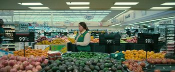 Movie still from “The Starling” (2021), directed by Theodore Melfi – A woman in a grocery store holding a bag of fruit; Wide shot, Over the shoulder angle