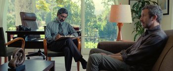 Movie still from “The Starling” (2021), directed by Theodore Melfi – A man sitting in a chair writing on a piece of paper; Medium shot, Over the shoulder angle