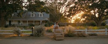 Movie still from “The Starling” (2021), directed by Theodore Melfi – A person sitting on a chair in a yard; Extreme Wide shot, Low angle