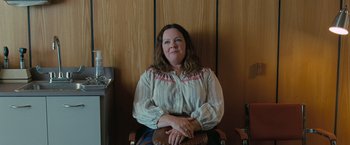 Movie still from “The Starling” (2021), directed by Theodore Melfi – A woman sitting in a chair in front of a wooden wall; Medium shot, Over the shoulder angle