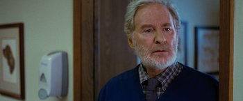 Movie still from “The Starling” (2021), directed by Theodore Melfi – An older man with a beard wearing a sweater and a tie; Close Up shot, Over the shoulder angle