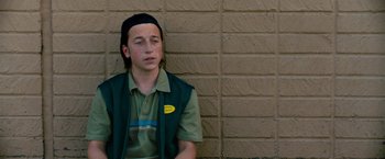 Movie still from “The Starling” (2021), directed by Theodore Melfi – A young man sitting against a brick wall; Close Up shot, Low angle