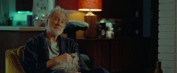 Movie still from “The Starling” (2021), directed by Theodore Melfi – An older man sitting in a chair holding a cat; Medium shot, Over the shoulder angle