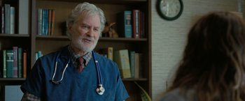 Movie still from “The Starling” (2021), directed by Theodore Melfi – An older man wearing a doctor's coat with a stethoscope around his neck; Medium shot, Over the shoulder angle