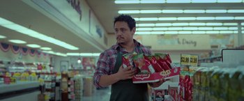 Movie still from “The Starling” (2021), directed by Theodore Melfi – A man holding a box of chips in a store; Medium shot, Low angle
