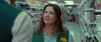 Movie still from “The Starling” (2021), directed by Theodore Melfi – A woman in a green vest is standing in front of a store; Close Up shot, Over the shoulder angle
