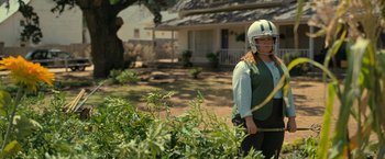 Movie still from “The Starling” (2021), directed by Theodore Melfi – A woman wearing a football helmet is standing in a garden; Wide shot, Over the shoulder angle