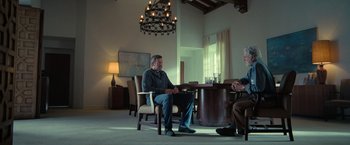 Movie still from “The Starling” (2021), directed by Theodore Melfi – Two men are sitting at a table in a living room; Wide shot, Over the shoulder angle