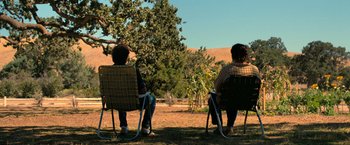 Movie still from “The Starling” (2021), directed by Theodore Melfi – Two people sitting in lawn chairs on a sunny day; Wide shot, High angle