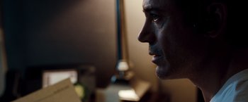 Movie still from “Due Date” (2010), directed by Todd Phillips – A man's face in a dimly - lit room; Close Up shot, Over the shoulder angle