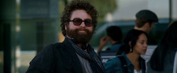 Movie still from “Due Date” (2010), directed by Todd Phillips – A man with a beard wearing sunglasses and a black jacket; Close Up shot, Over the shoulder angle