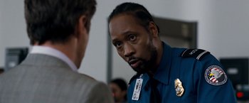 Movie still from “Due Date” (2010), directed by Todd Phillips – A police officer talking to a man in a suit; Close Up shot, Over the shoulder angle