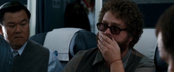 Movie still from “Due Date” (2010), directed by Todd Phillips – A man sitting on top of an airplane holding his hands to his mouth; Close Up shot, Over the shoulder angle
