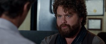 Movie still from “Due Date” (2010), directed by Todd Phillips – A man with a beard is sitting in a car; Close Up shot, Over the shoulder angle